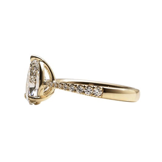 Pear-shaped solitaire diamond engagement ring featuring a pavé diamond band.