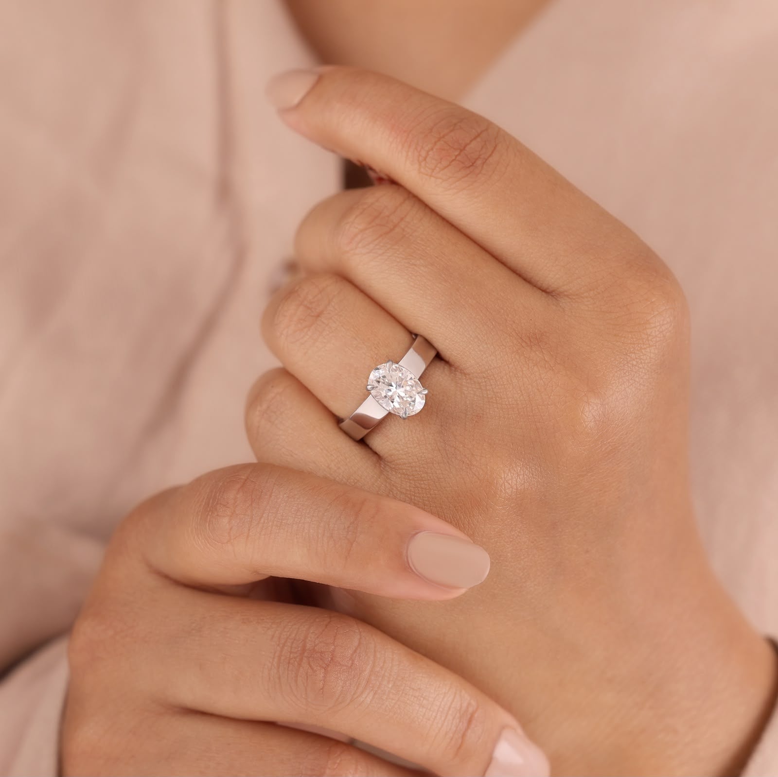 Oval-cut center stone set in a polished white gold wide band engagement ring.