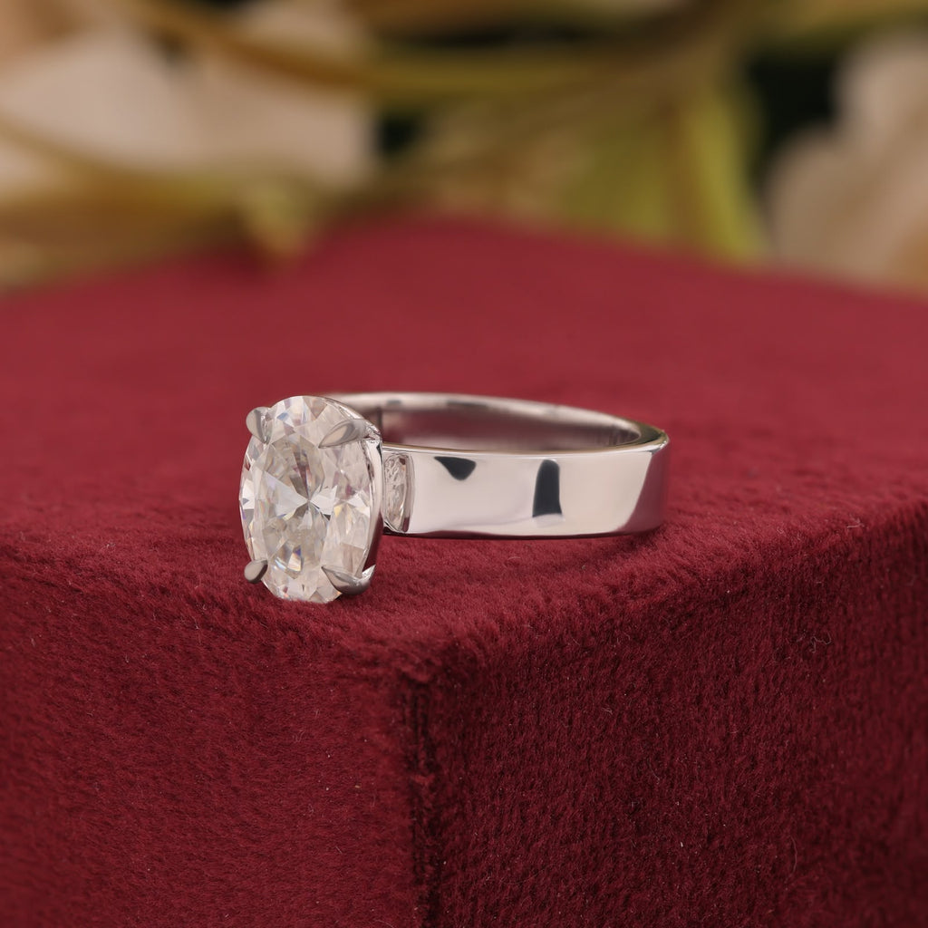 Oval-cut center stone set in a polished white gold wide band engagement ring.