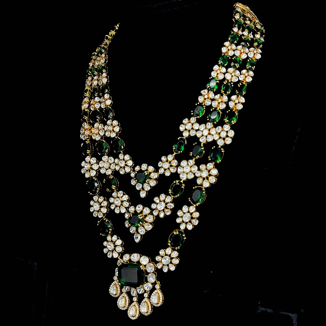 Emerald-tinted gemstone beads and drops, culminating in a grand central emerald pendant.
