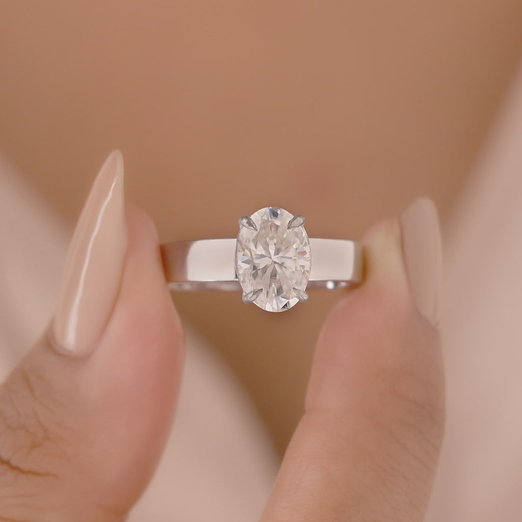 Oval-cut center stone set in a polished white gold wide band engagement ring.